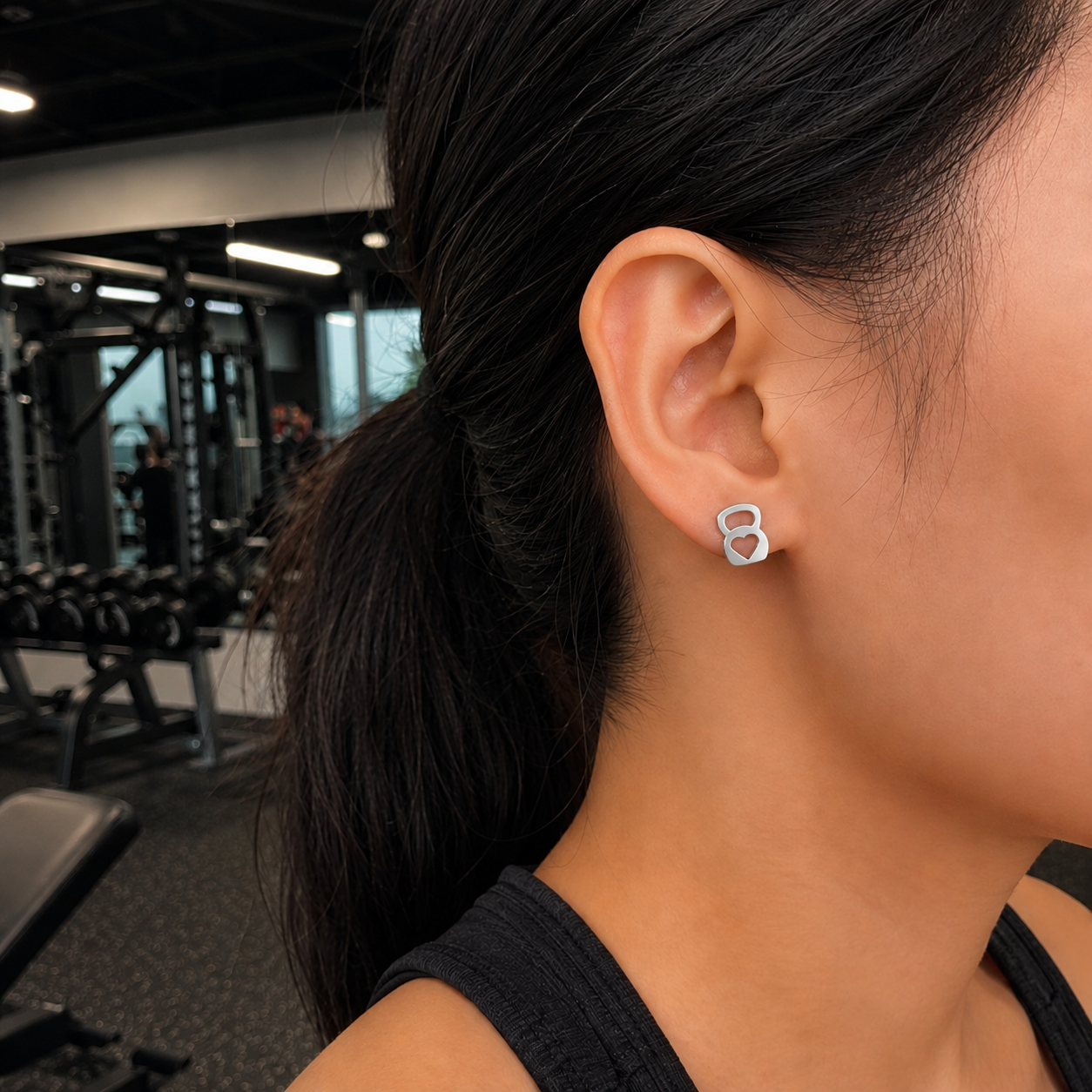 Person wearing silver earrings in a gym setting
