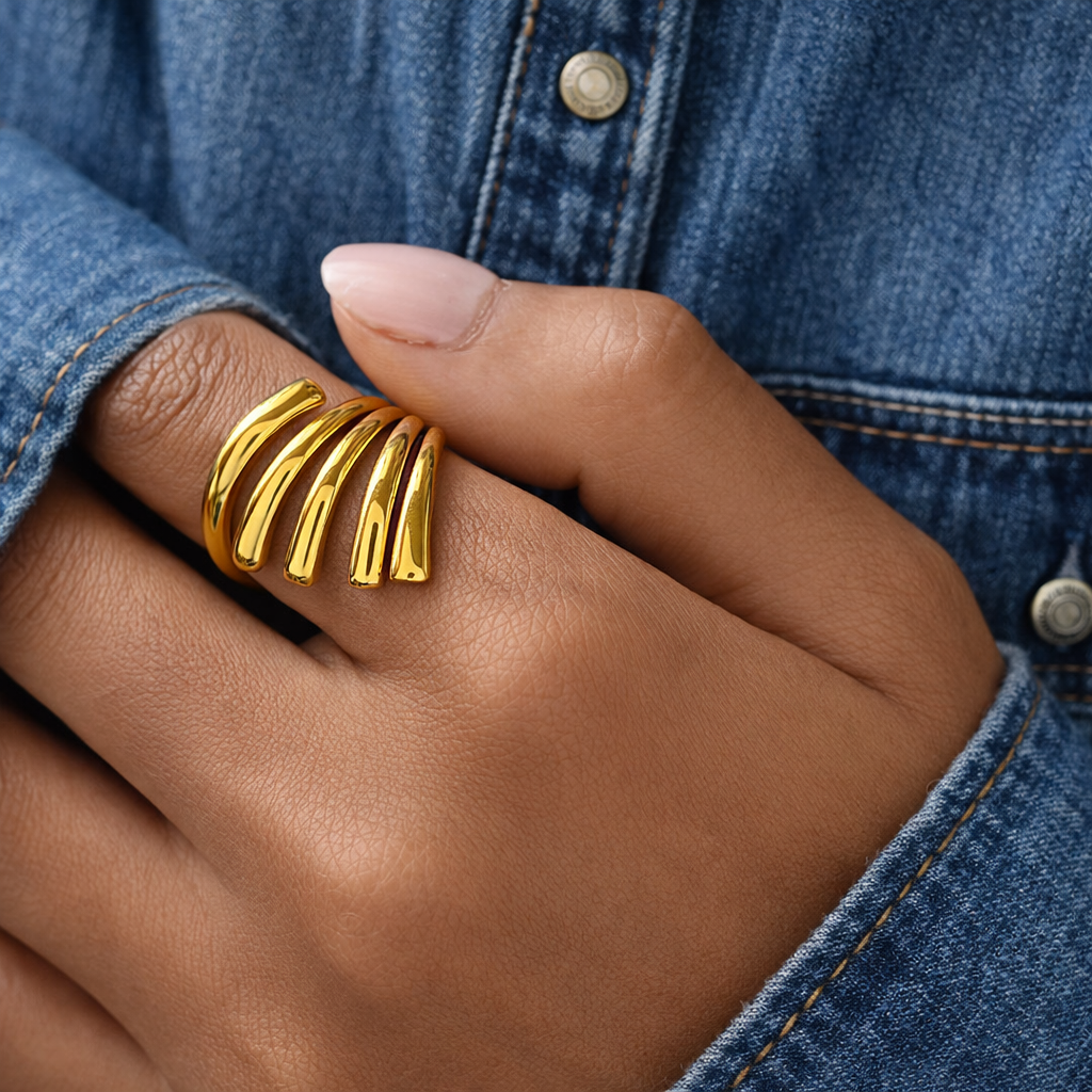 Gold ring on a finger with a denim background