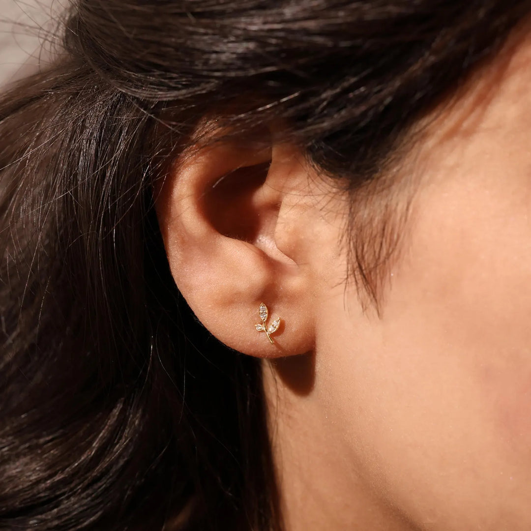 Close-up of an ear wearing a gold earring with a blurred background