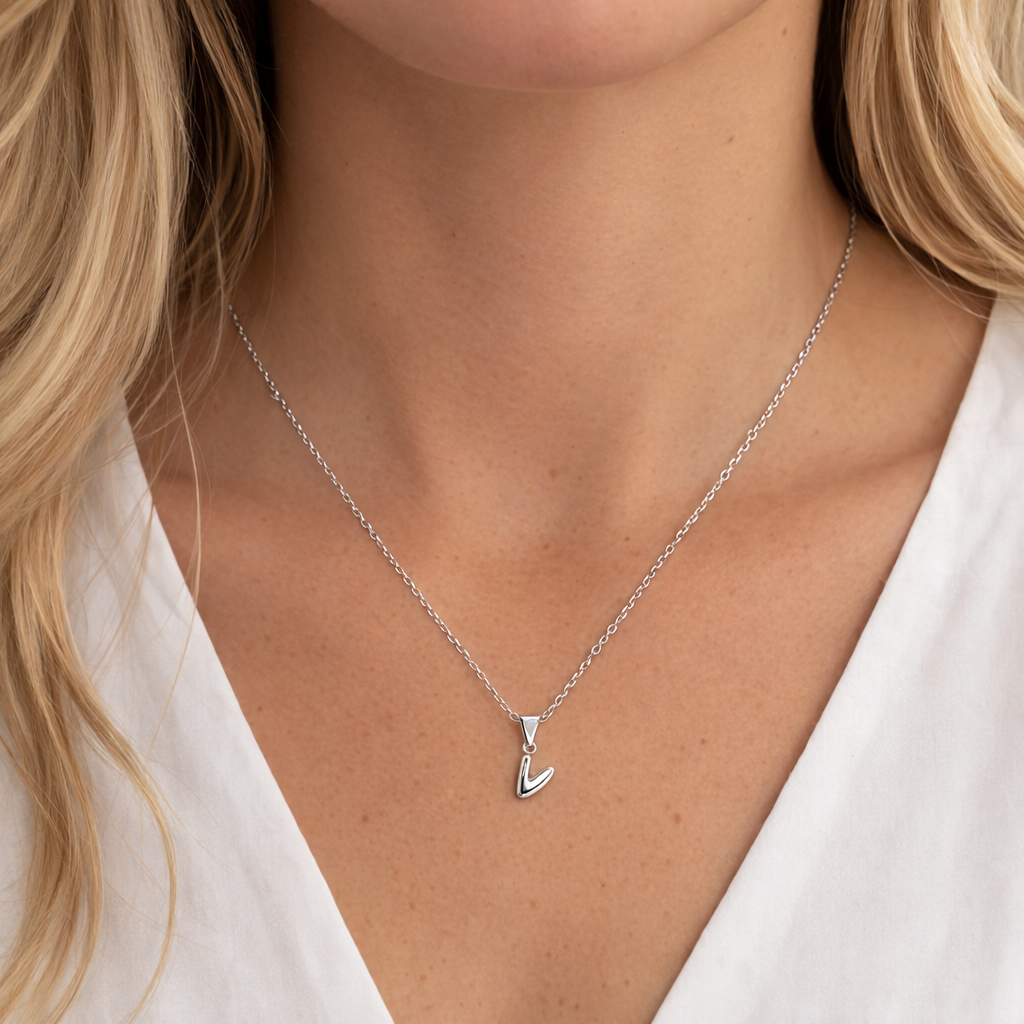 Silver necklace with a pendant worn by a person against a neutral background