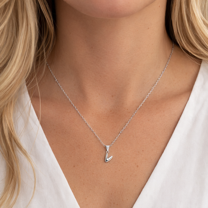 Silver necklace with a pendant worn by a person against a neutral background