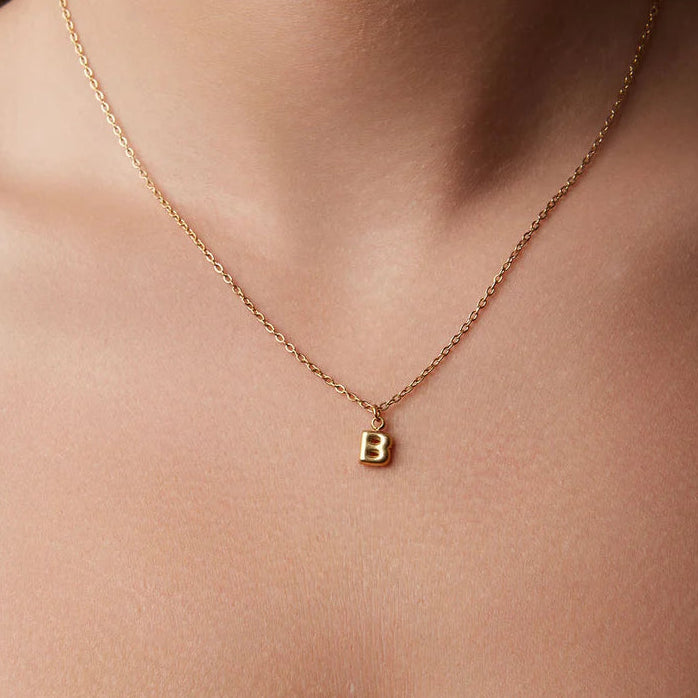 Gold necklace with a 'B' pendant on a person's neck