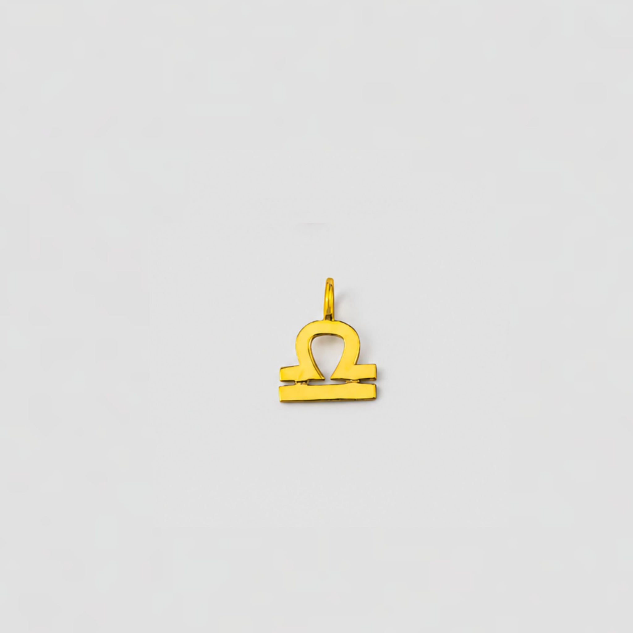 Gold Libra zodiac pendant on a light gray background