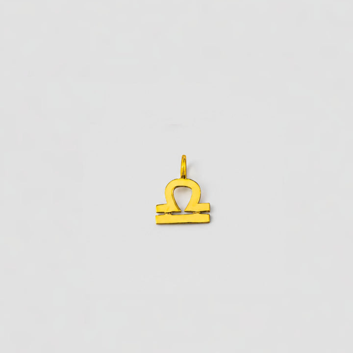 Gold Libra zodiac pendant on a light gray background