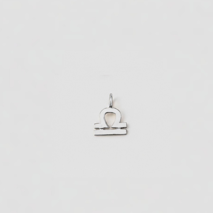 Silver Libra zodiac sign pendant on a light gray background