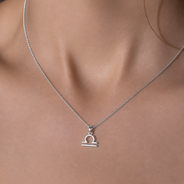 Silver Libra zodiac necklace on a model's neck