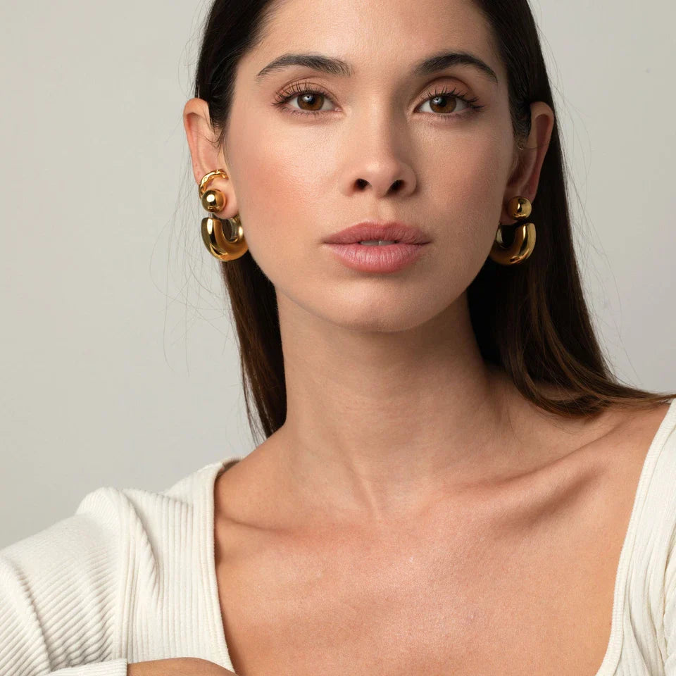 Woman wearing gold hoop earrings against a neutral background