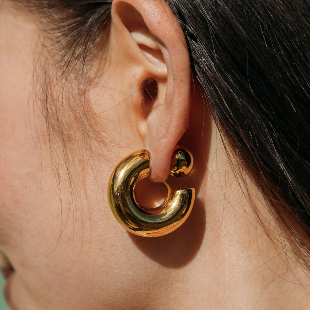 Close-up of a gold hoop earring worn by a person with dark hair.