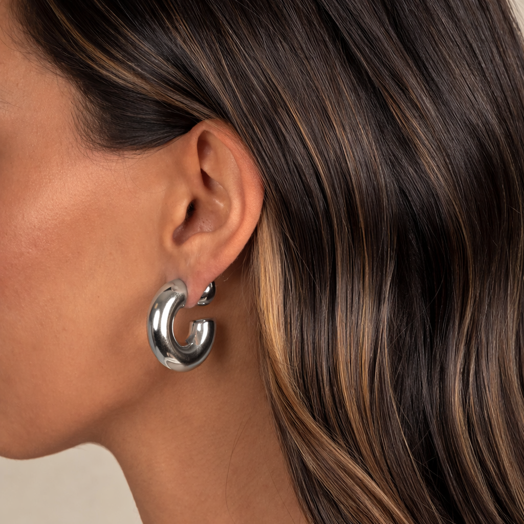Close-up of a woman wearing a silver hoop earring with a neutral background