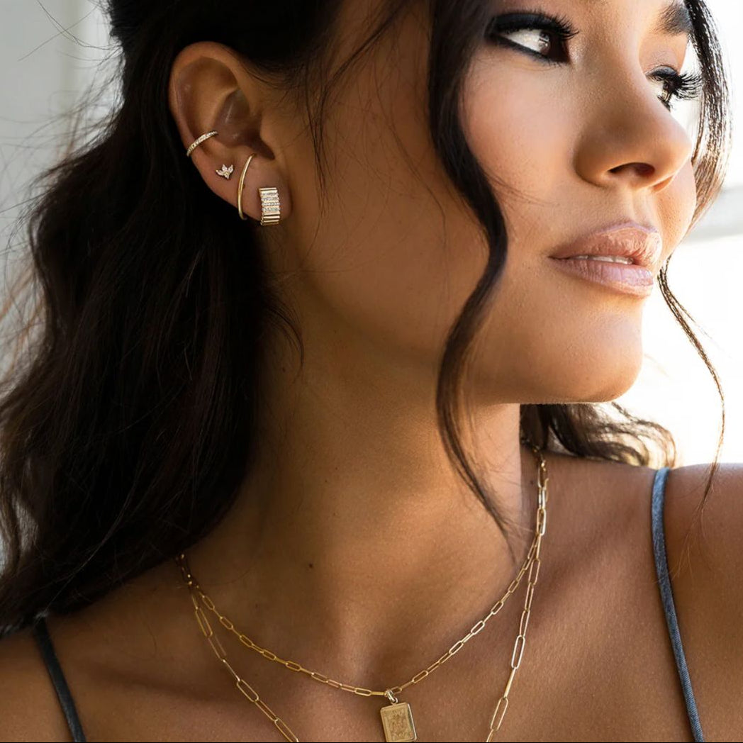 Close-up of a woman wearing gold earrings and necklaces with a blurred background