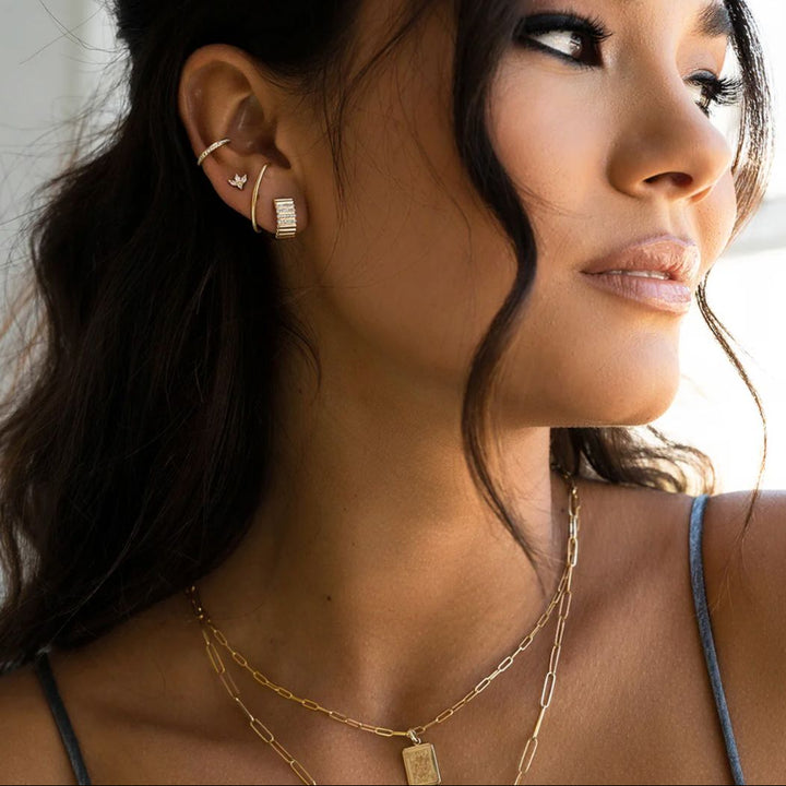 Close-up of a woman wearing gold earrings and necklaces with a blurred background
