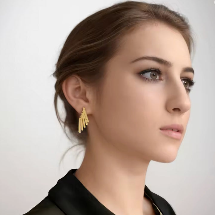 Woman wearing gold earrings against a plain background
