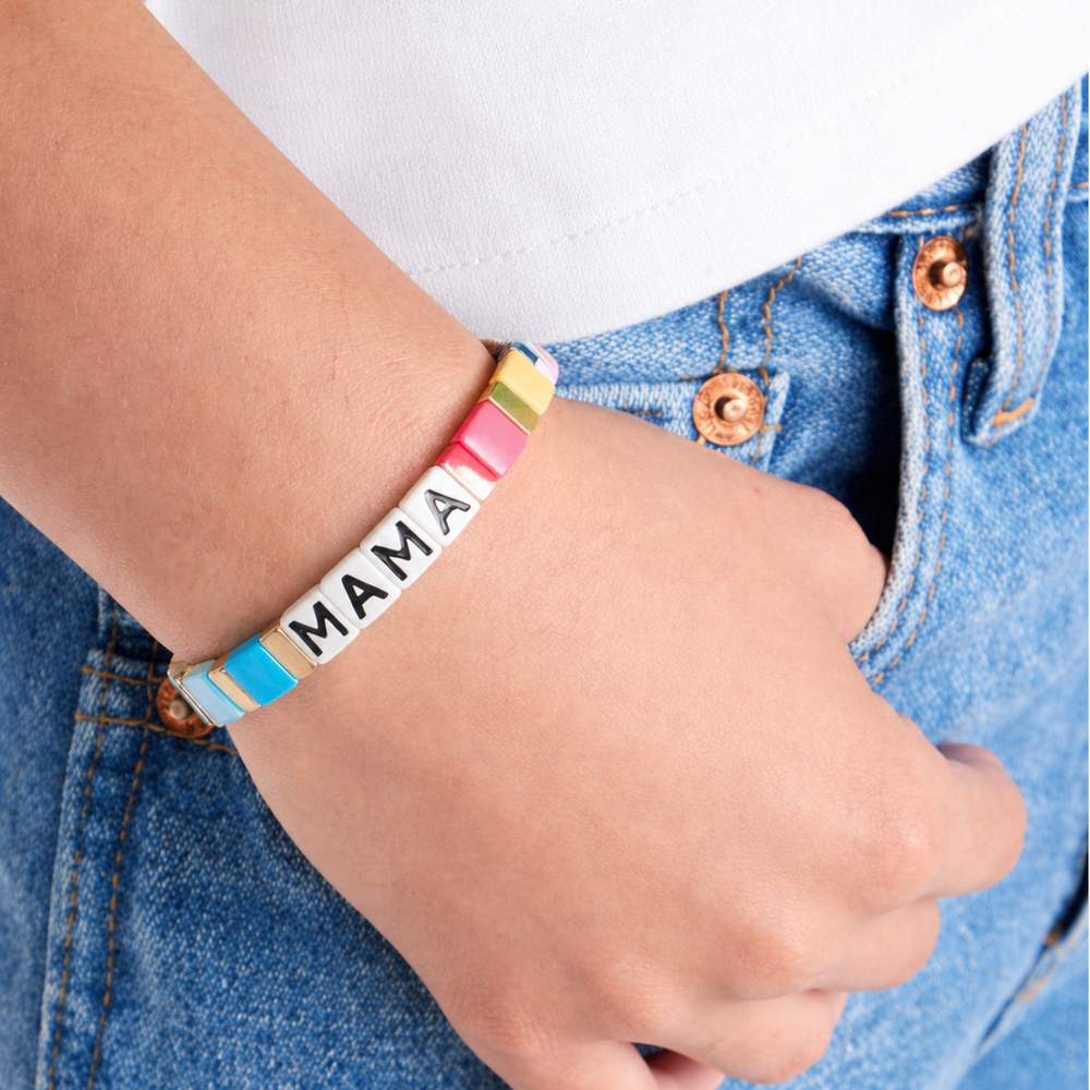 Child's hand wearing a colorful 'MAMA' bracelet on a white background