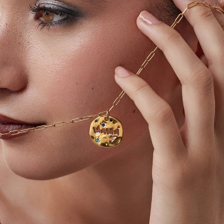 Close-up of a woman wearing a gold necklace with a pendant.