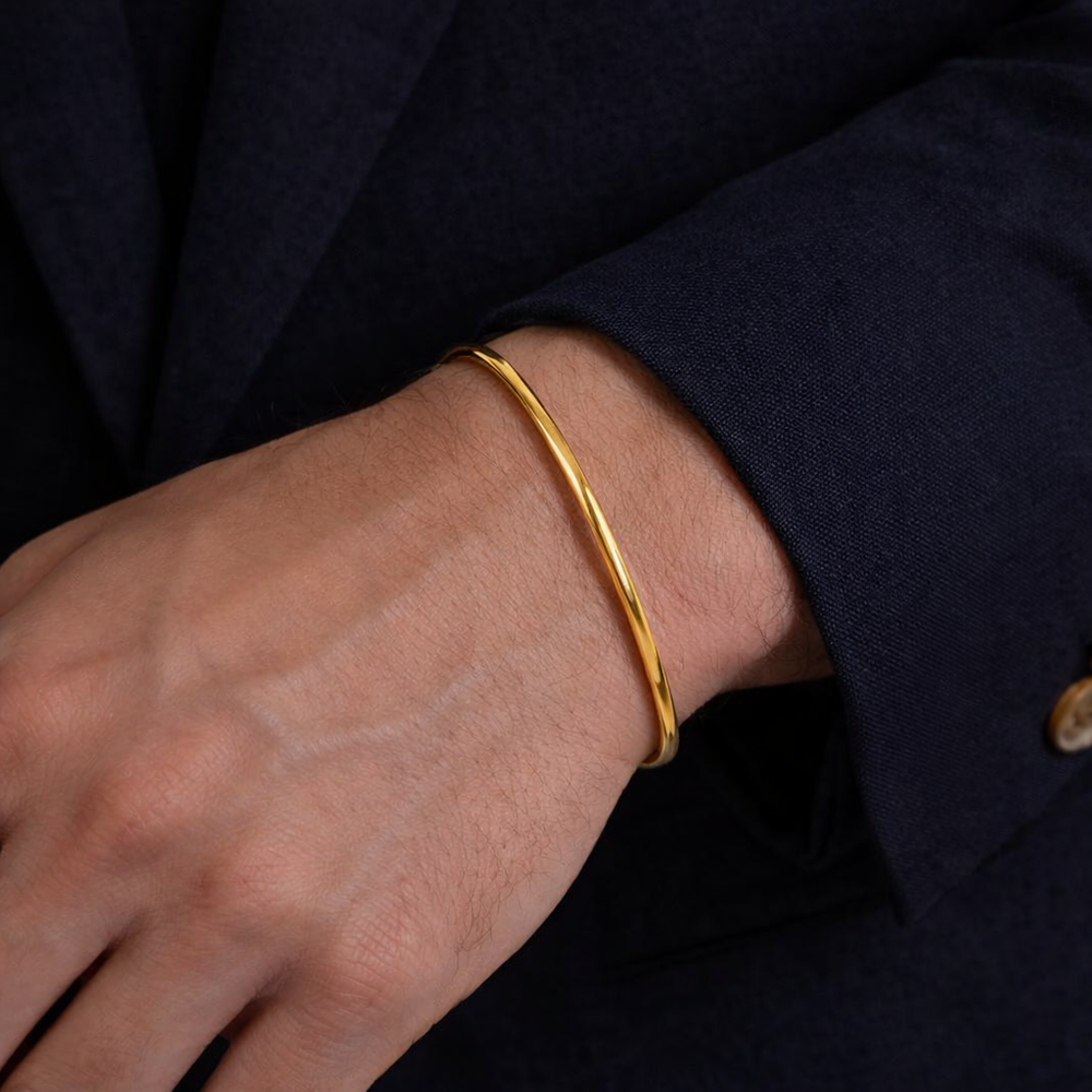 Gold bracelet on a wrist with a dark background