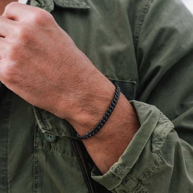 Person wearing a black chain bracelet on a green shirt