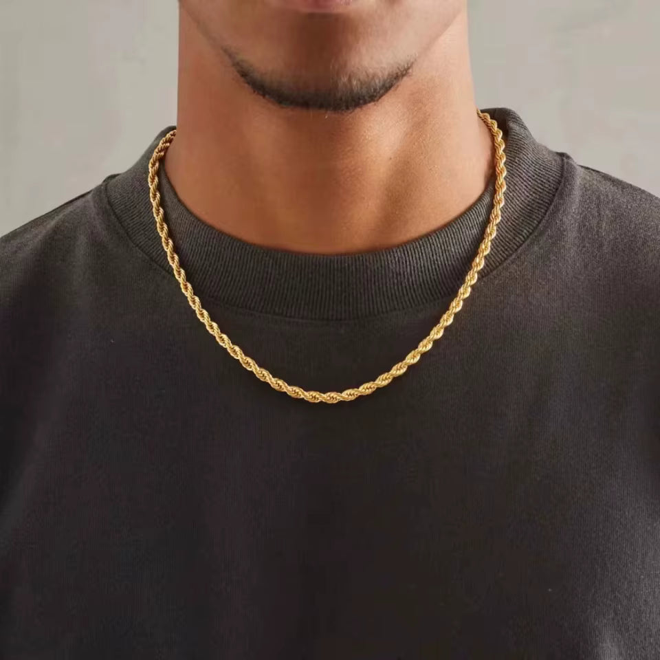 Gold chain necklace worn by a person on a plain background