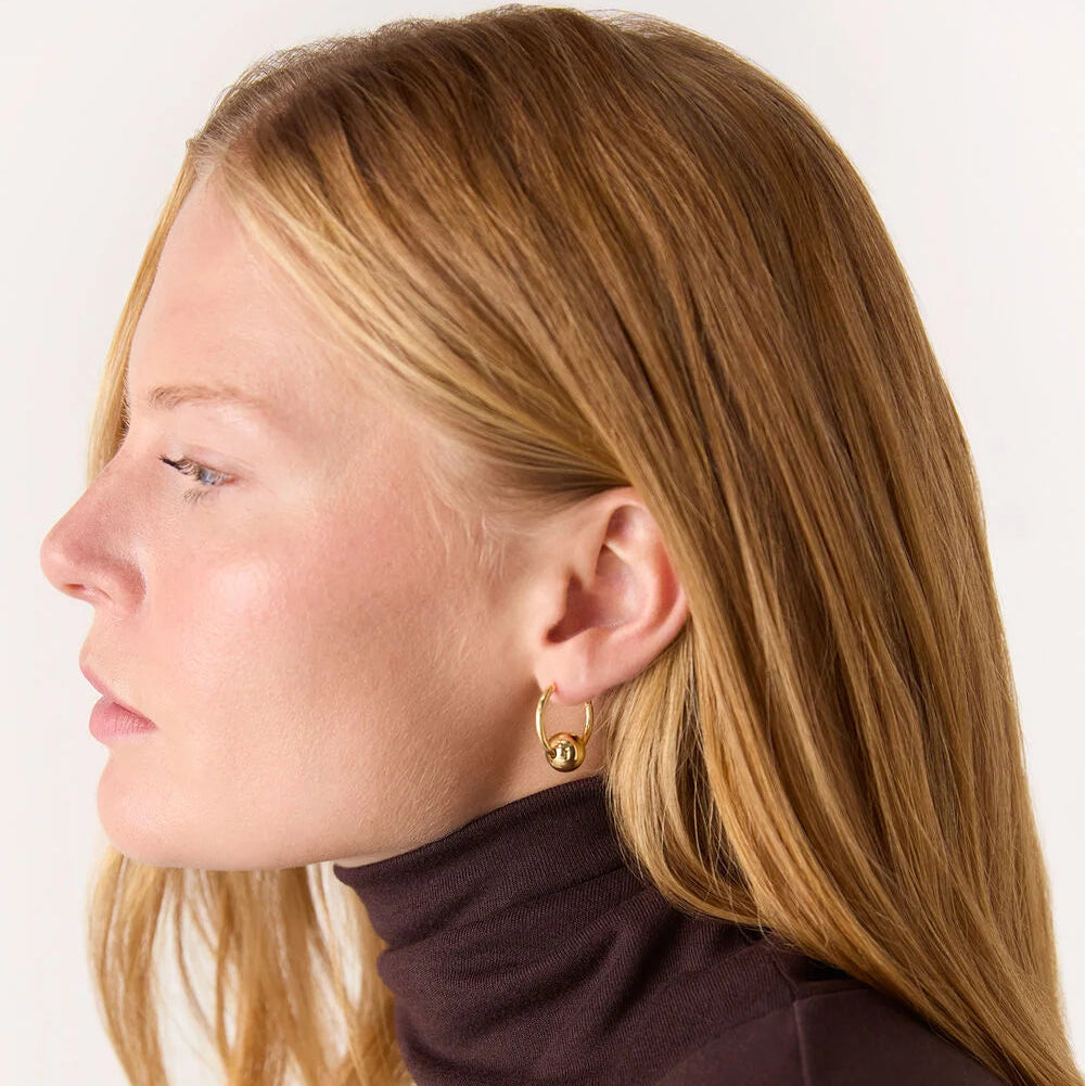 Woman wearing a brown turtleneck sweater with a plain background