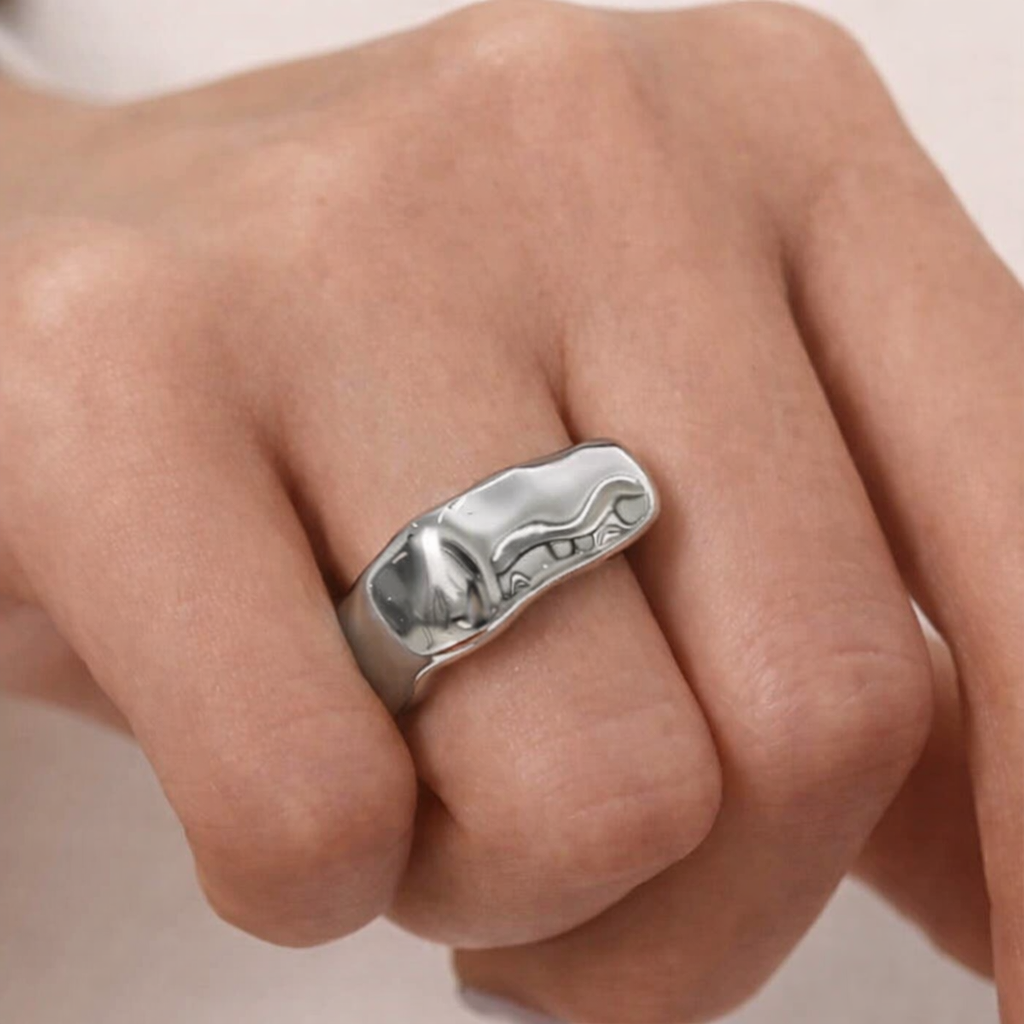 Silver ring on a person's finger against a neutral background