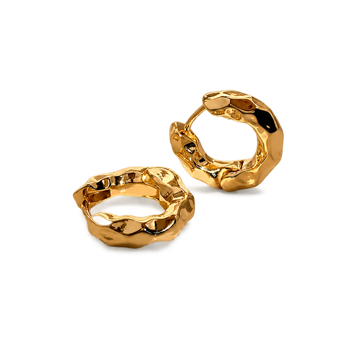 A pair of chunky, textured gold huggie hoop earrings with a polished, organic, hammered finish, displayed on a clean white background.