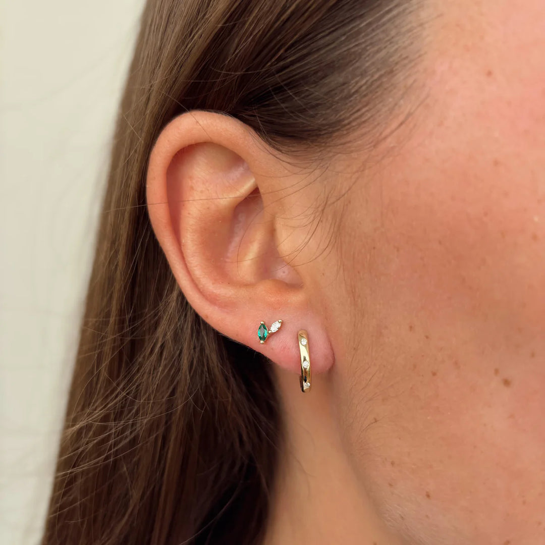 Close-up of an ear wearing a small earring and gold hoop.