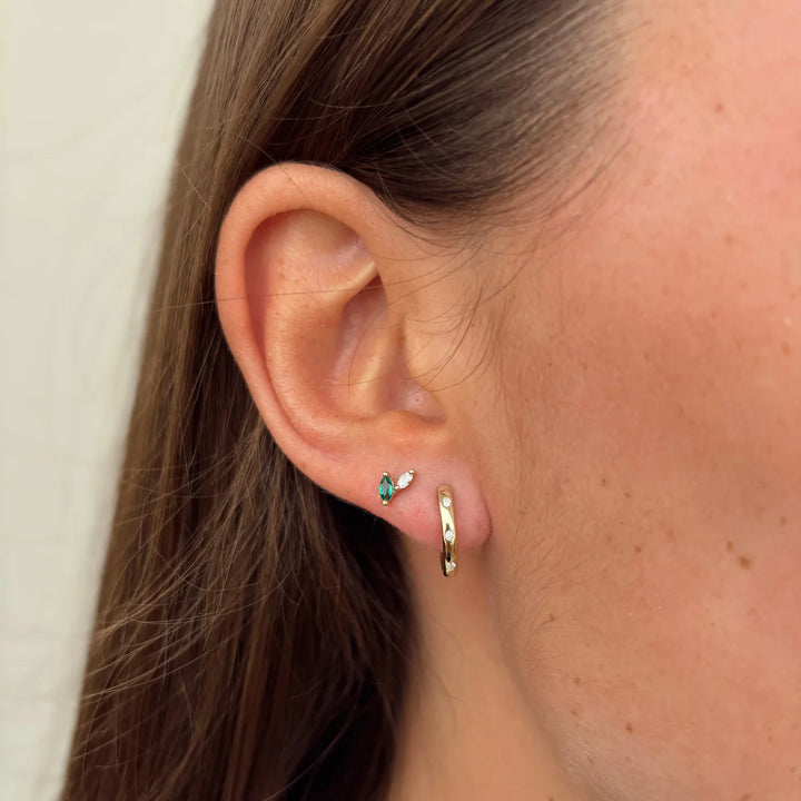 Close-up of an ear wearing a small earring and gold hoop.
