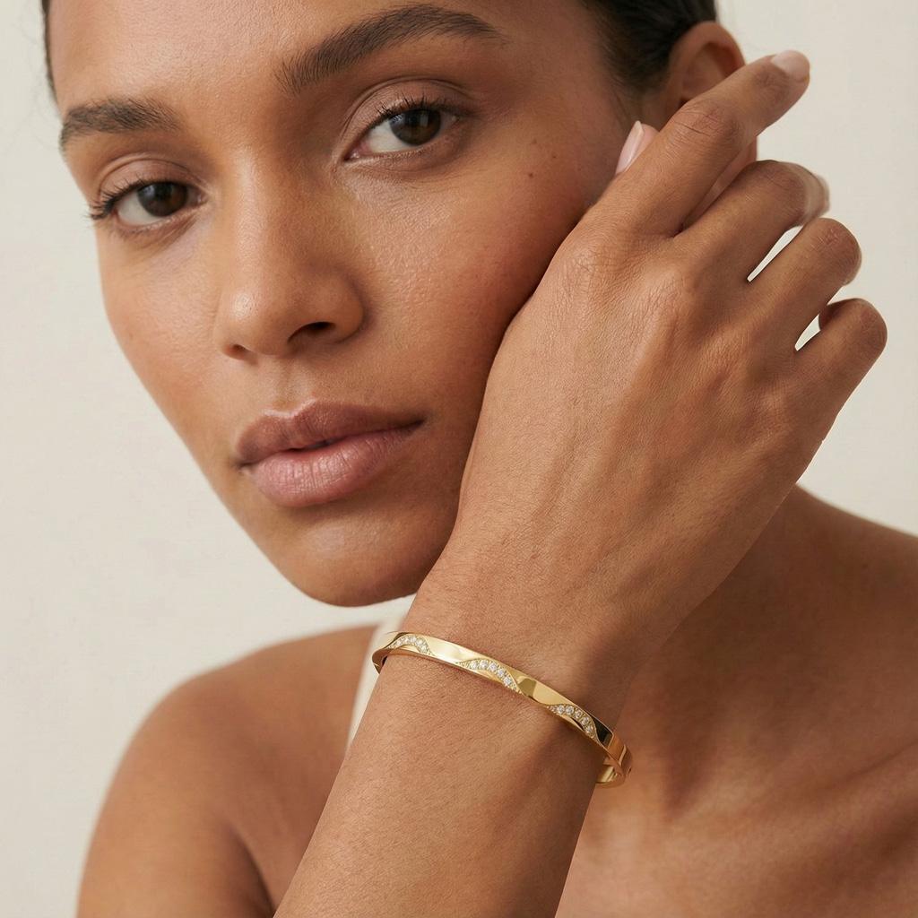 Woman wearing a gold bracelet on a neutral background