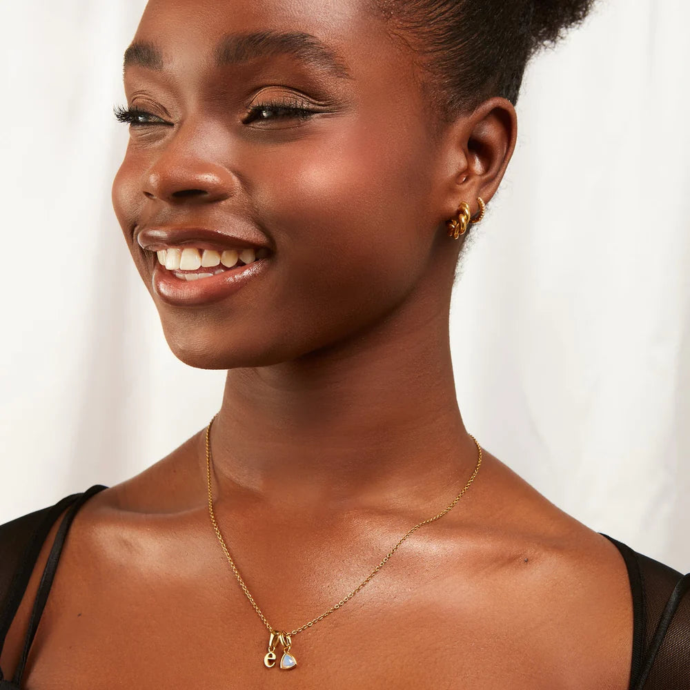 Woman wearing a gold necklace and earrings on a white background