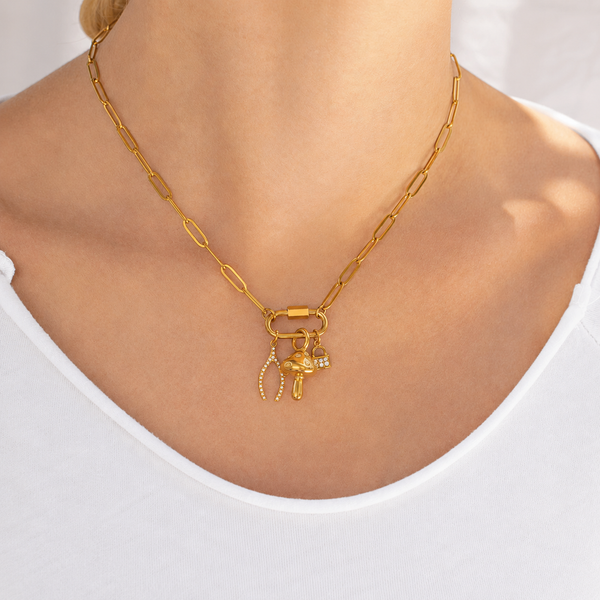 Gold necklace with charms on a person wearing a white top