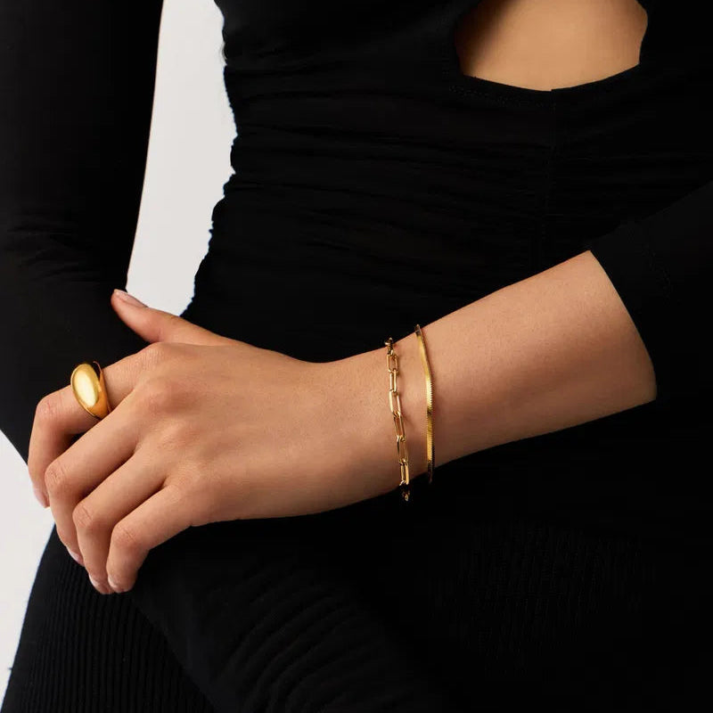 Gold ring and bracelets on a person's wrist against a black background