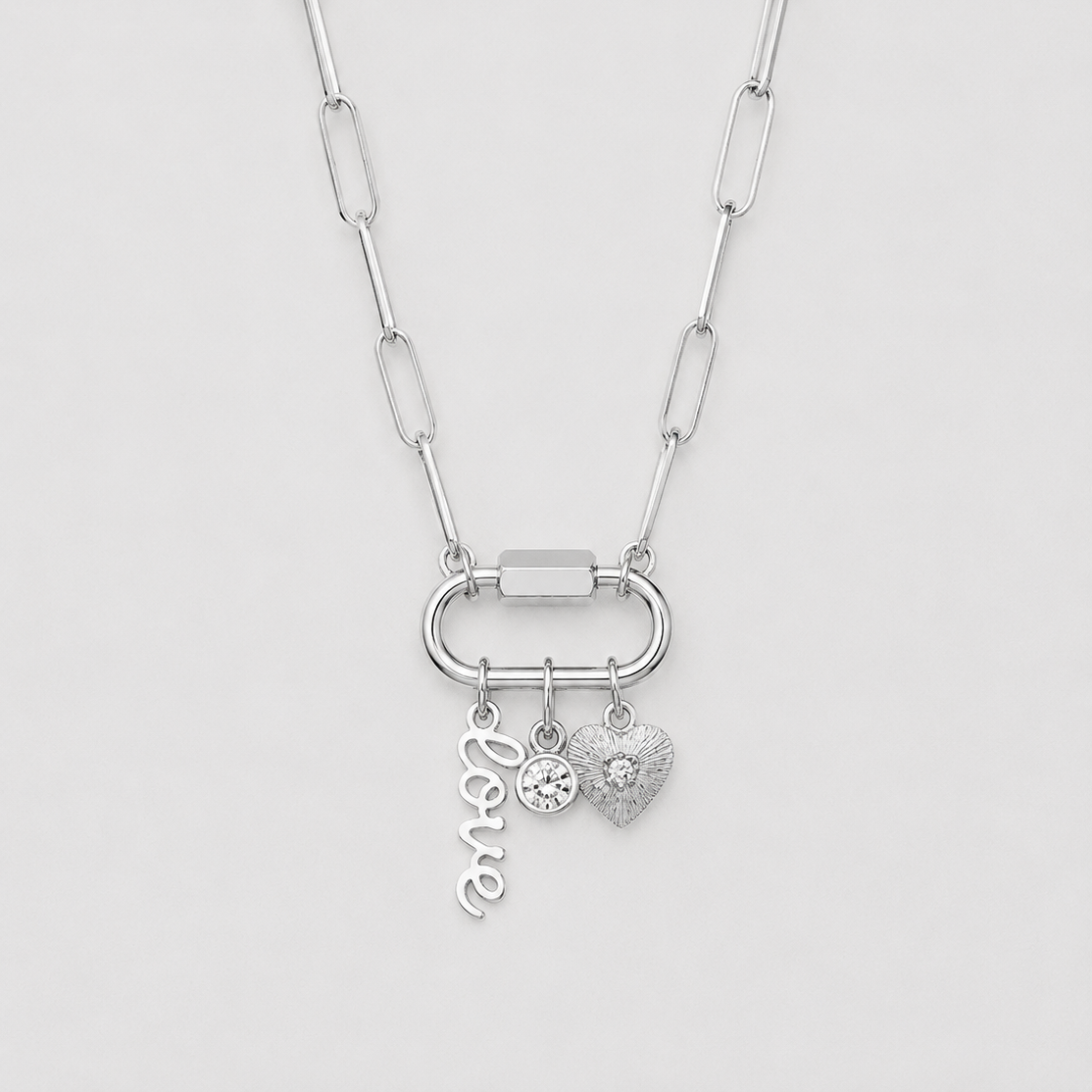 Silver necklace with heart and letter charm on a light gray background