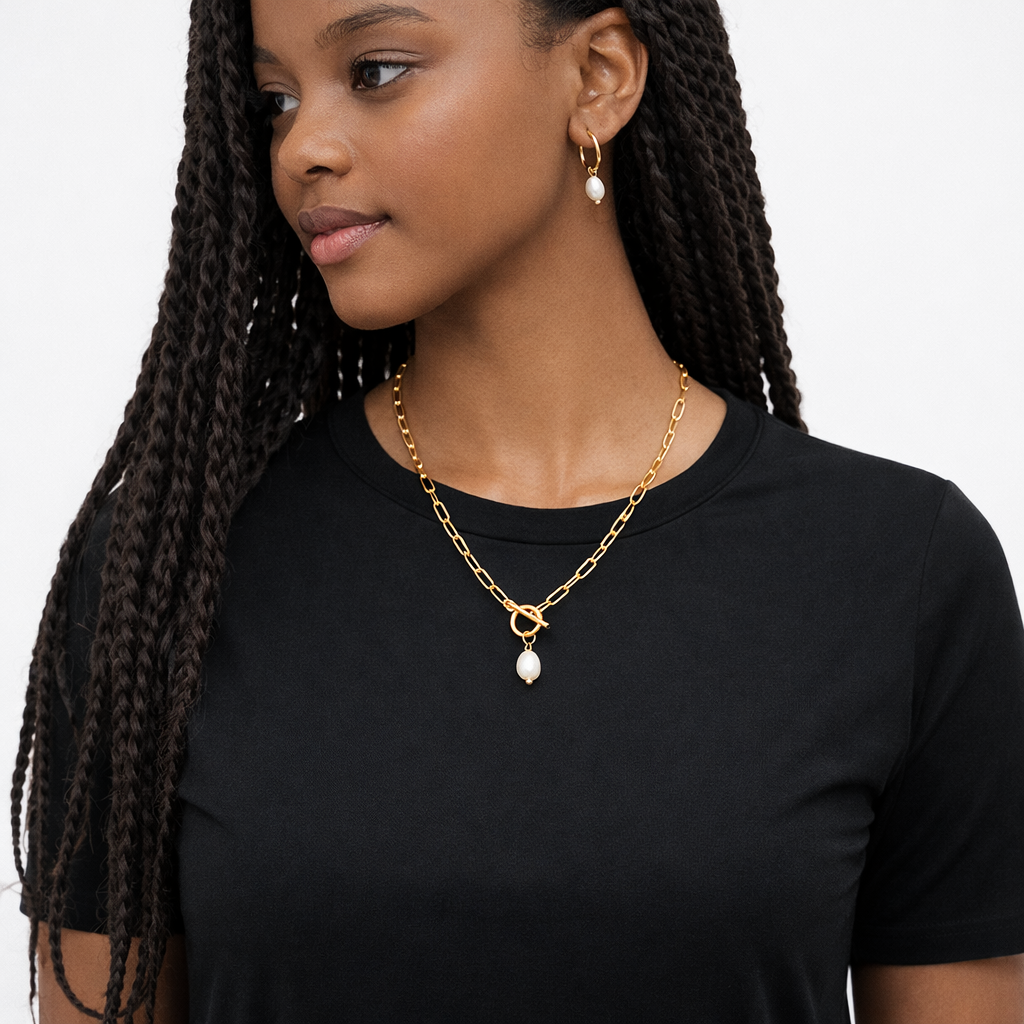 Woman wearing a gold necklace with a pendant on a plain background