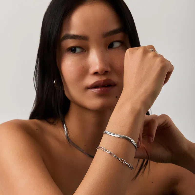 Woman wearing silver jewelry on a plain background
