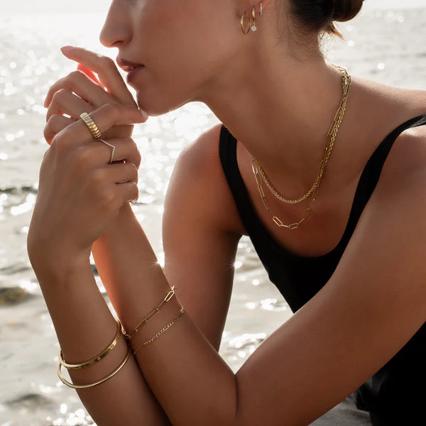Woman wearing gold jewelry with a blurred beach background