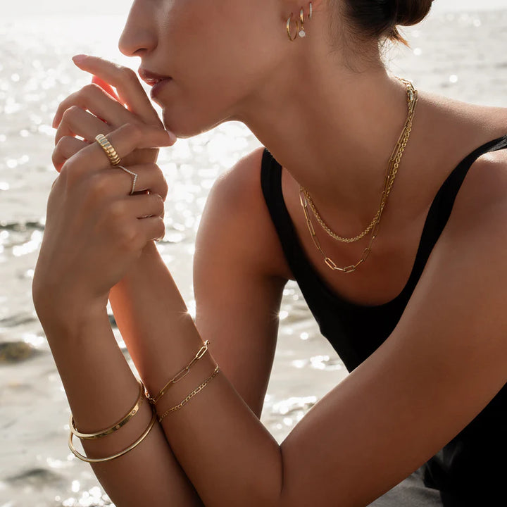 Woman wearing gold jewelry with a blurred beach background