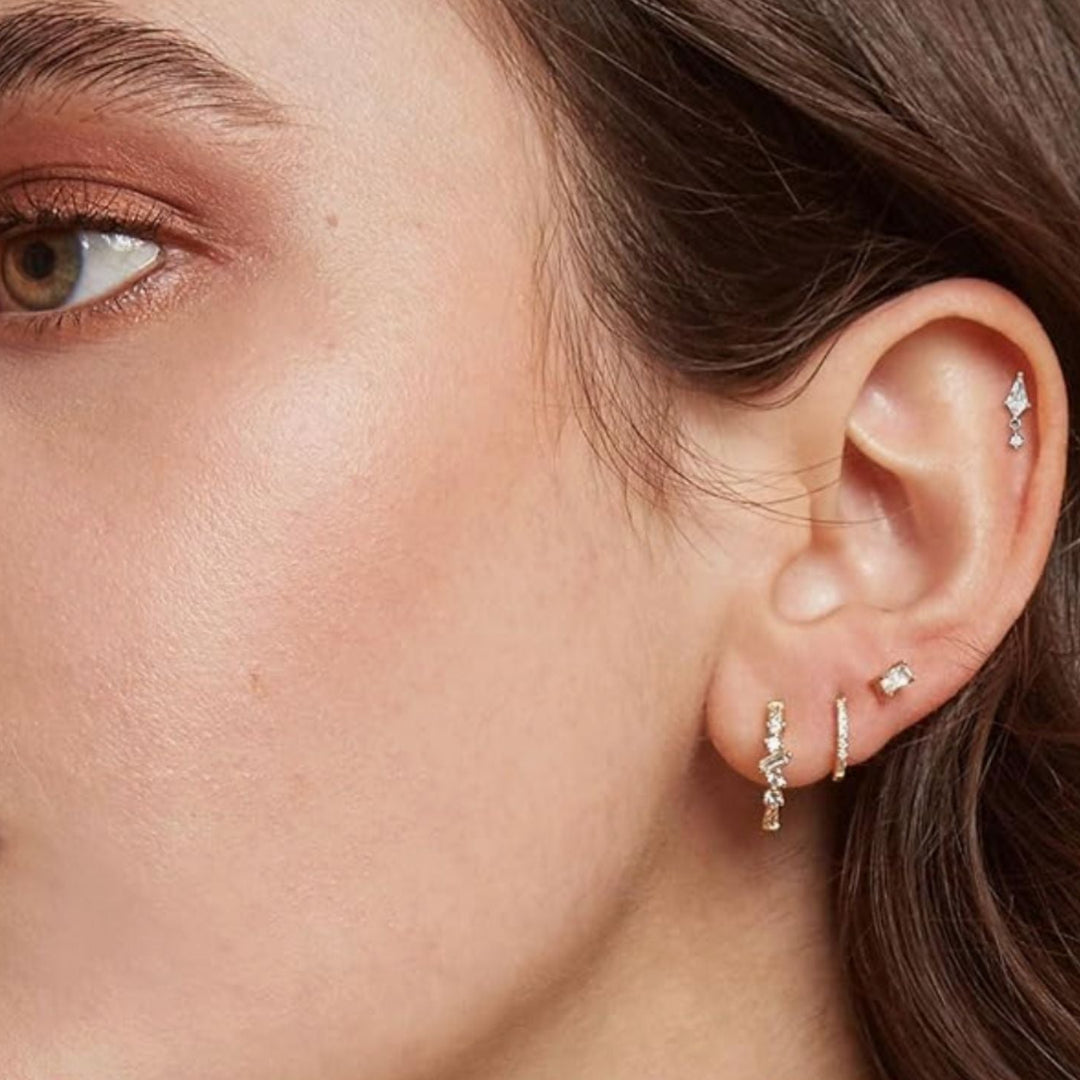 Close-up of a person's ear with multiple diamond earrings.