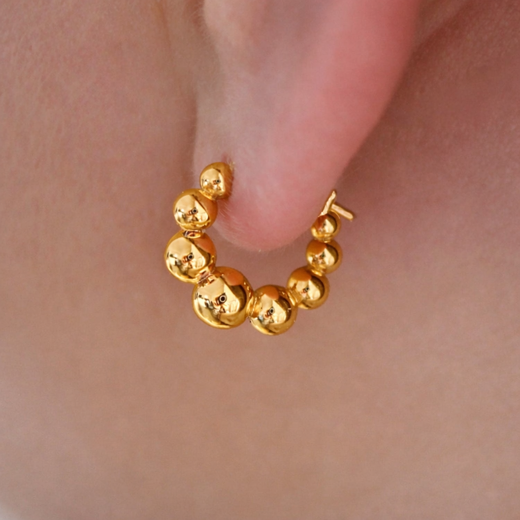 Gold hoop earring worn on an ear
