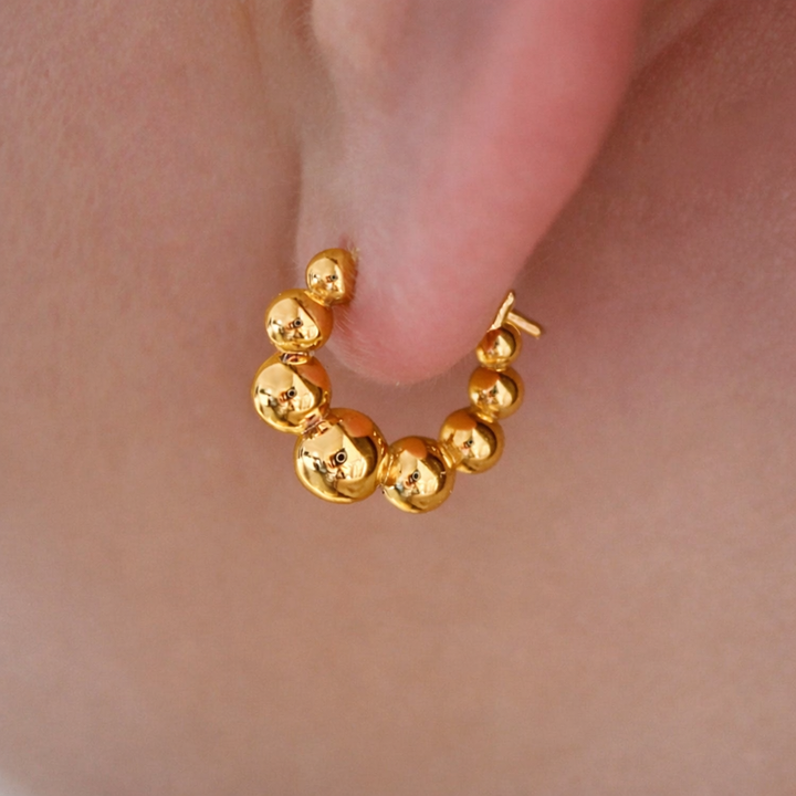 Gold hoop earring worn on an ear