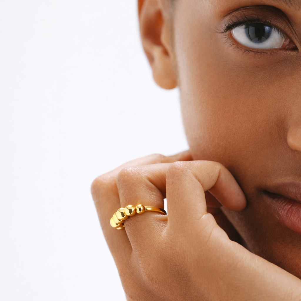 Close-up of a person wearing a gold ring on a white background