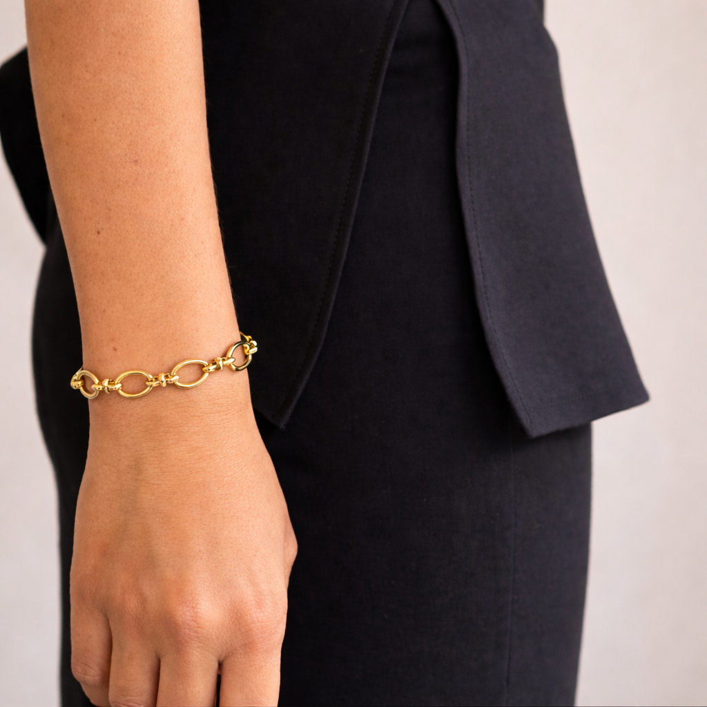 Gold bracelet on a person's wrist with a plain background