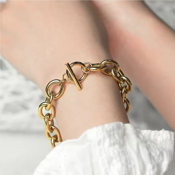 Gold chain bracelet on a wrist with a blurred background