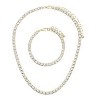 Gold necklace and bracelet set with clear gemstones on a white background