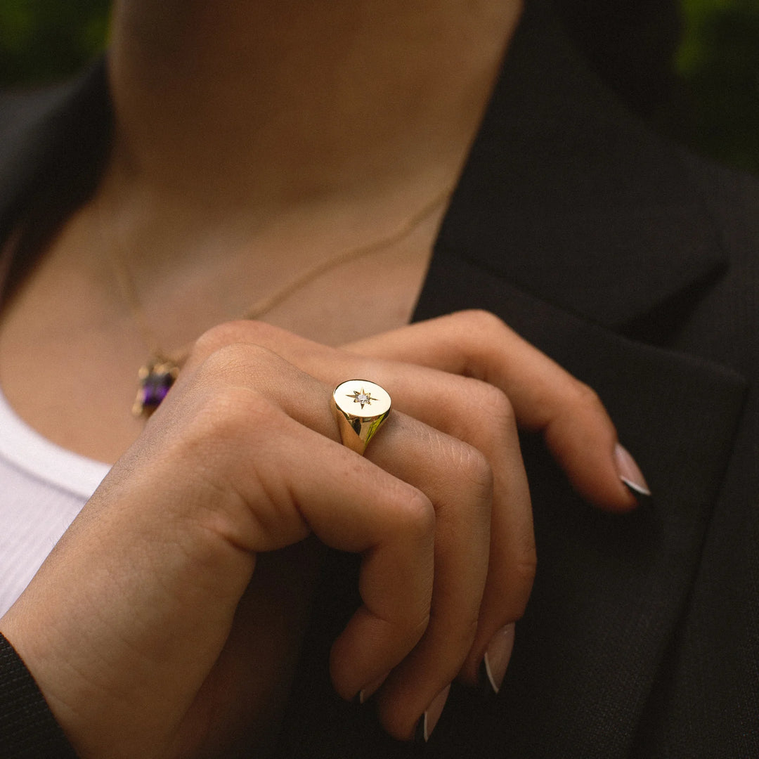 Close-up of a person wearing a gold ring with a star design.