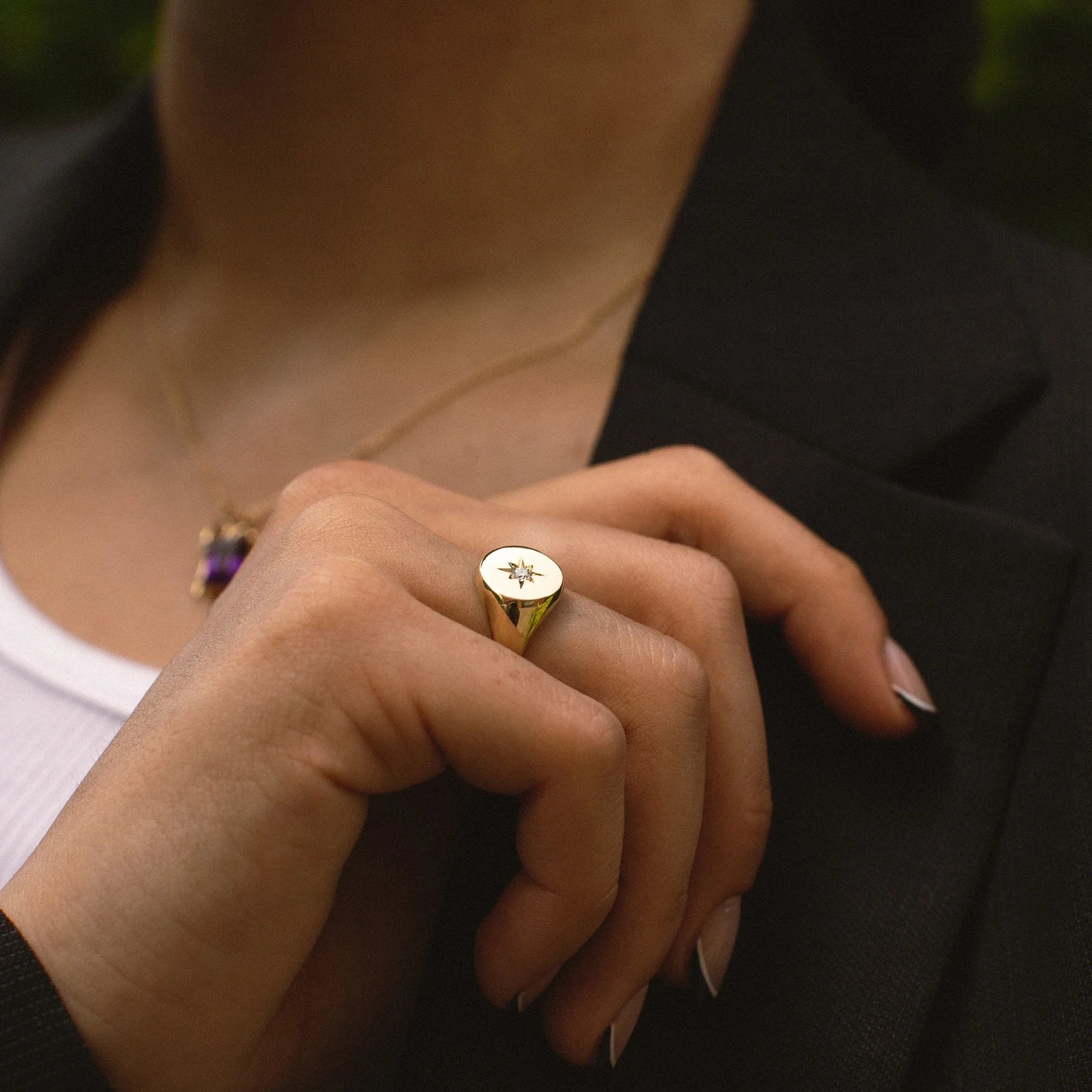 Close-up of a person wearing a gold ring with a star design.