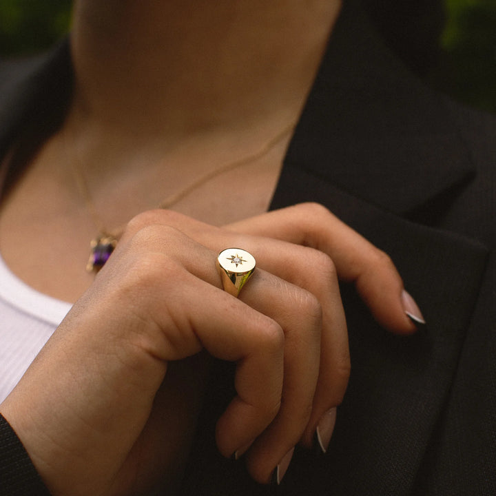 Close-up of a person wearing a gold ring with a star design.