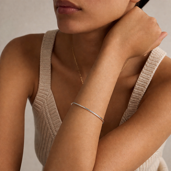 Woman wearing a silver bracelet on her wrist with a neutral background