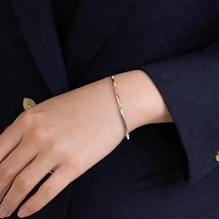 Person wearing a silver bracelet on a dark suit background
