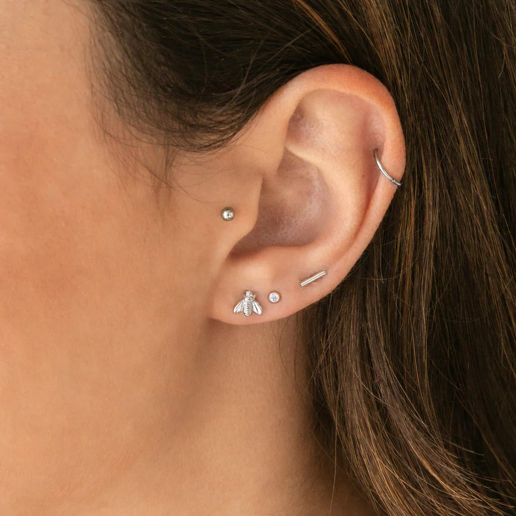 Close-up of an ear with multiple silver earrings