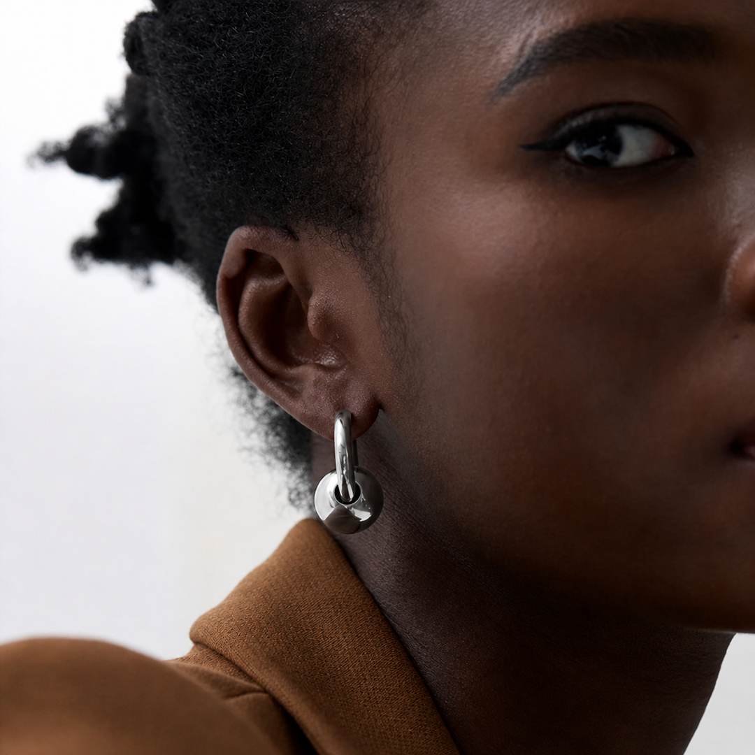 Close-up of a person wearing a silver hoop earring with a blurred background