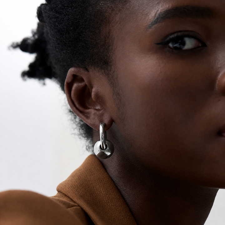 Close-up of a person wearing a silver hoop earring with a blurred background